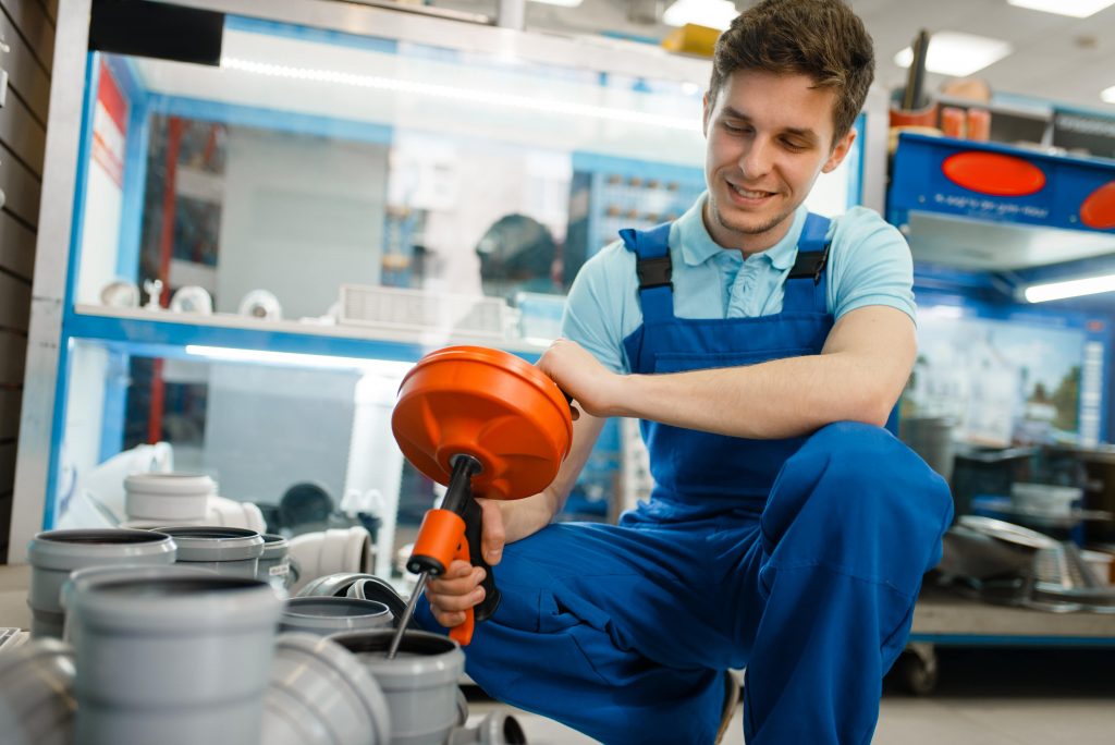 Klempner kniet und nutzt orangenes Werkzeug Die Vorteile der Innungsmitgliedschaft